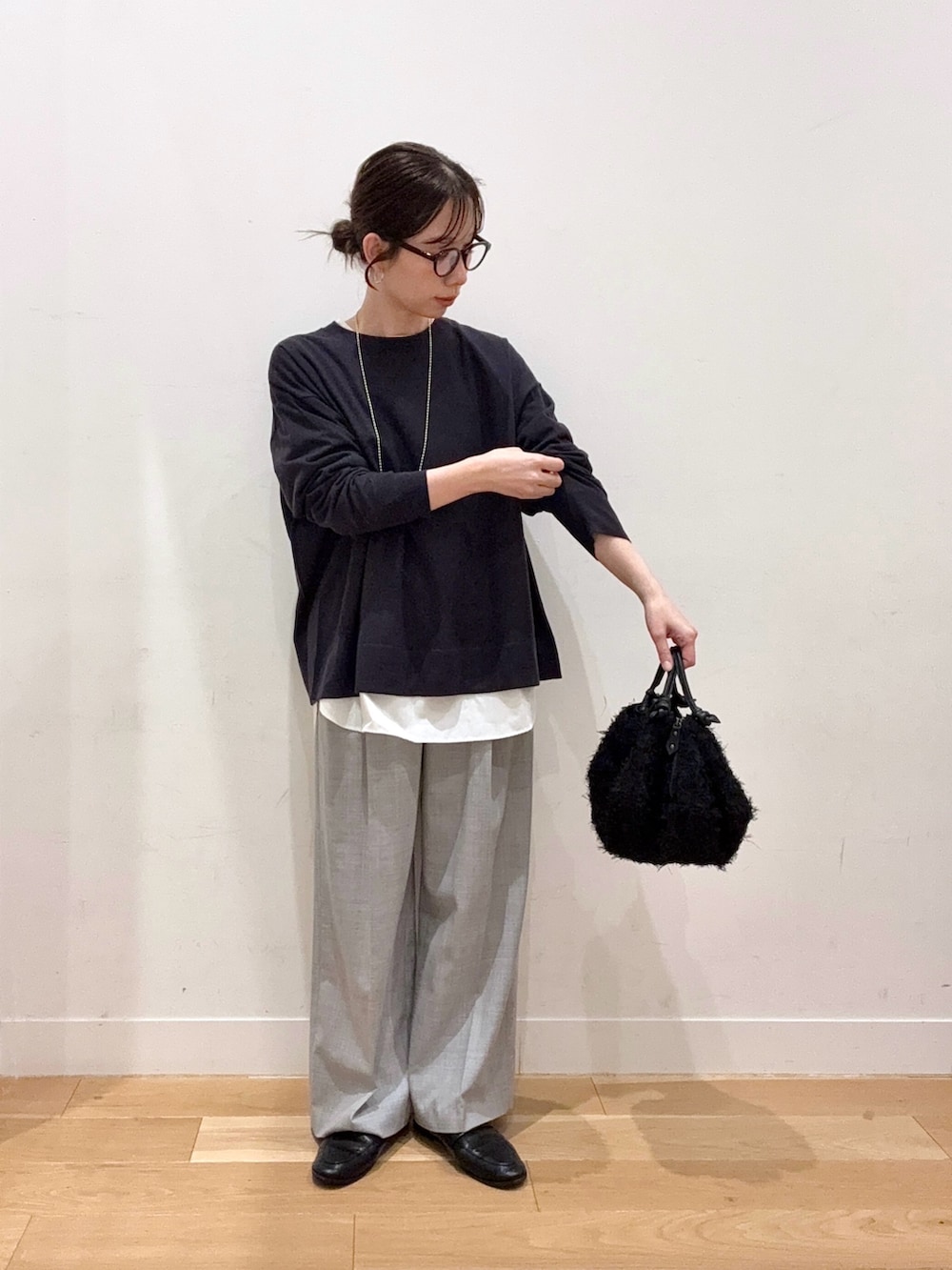 グレー系のニット/セーター、ホワイト系のダウンジャケット/コート、ブラック系のハンドバッグを着用したレディースの秋コーディネートの4枚目の写真