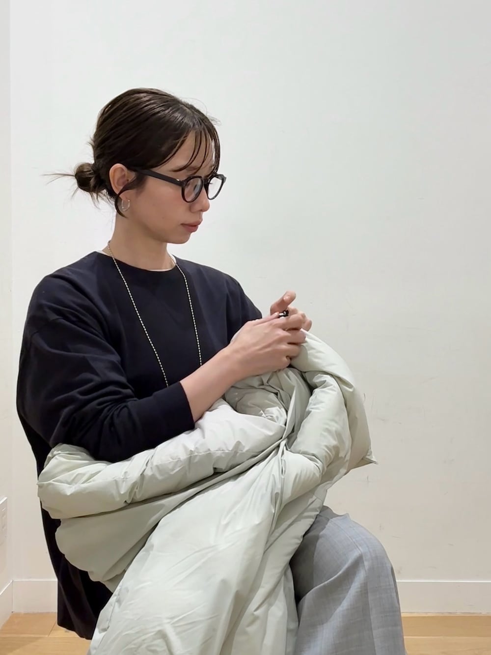 グレー系のニット/セーター、ホワイト系のダウンジャケット/コート、ブラック系のハンドバッグを着用したレディースの秋コーディネートの8枚目の写真