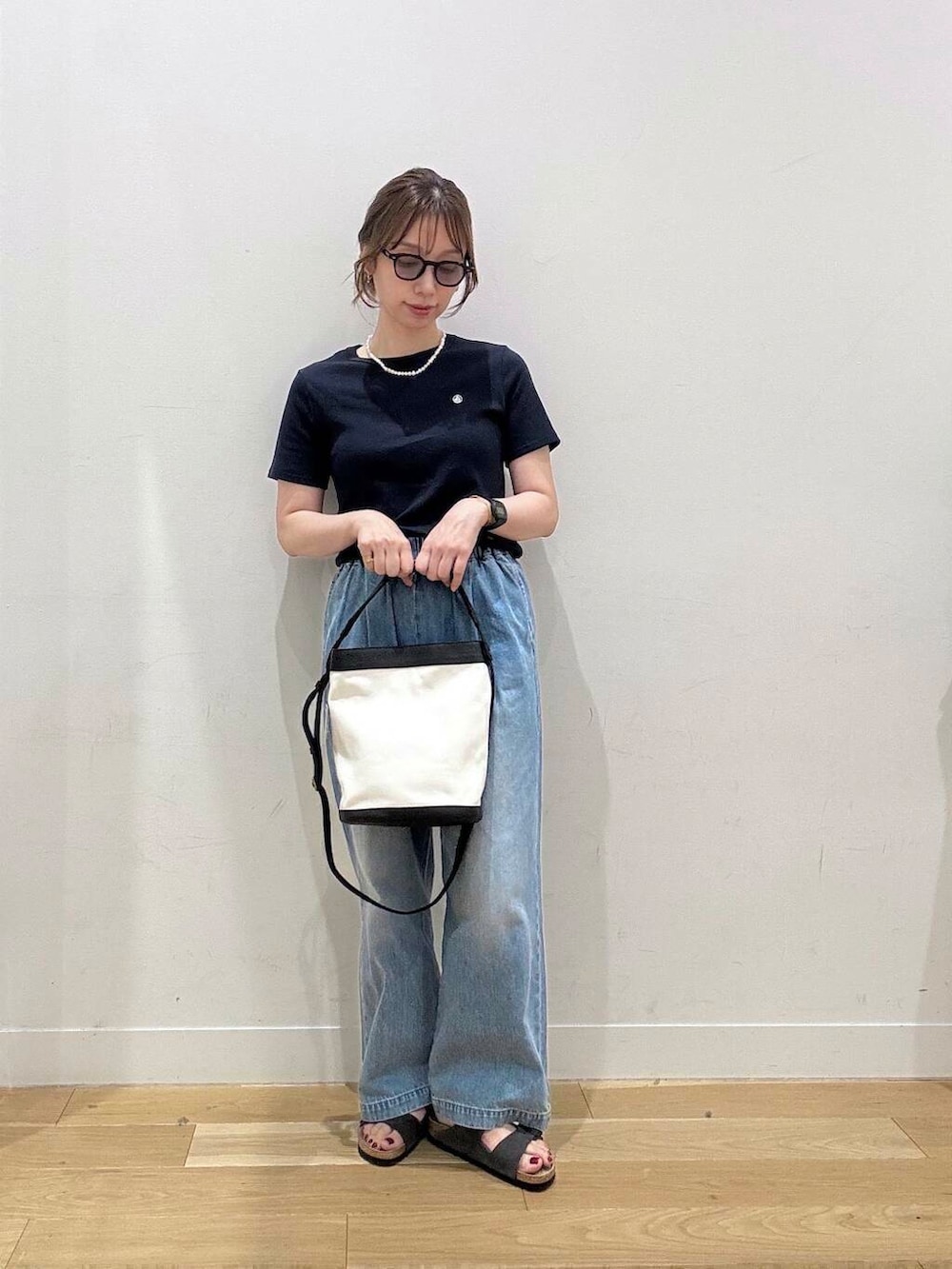 ブルー系のデニムパンツ、ブラック系のショルダーバッグ、グレー系のサンダルを着用したレディースの夏コーディネートの4枚目の写真