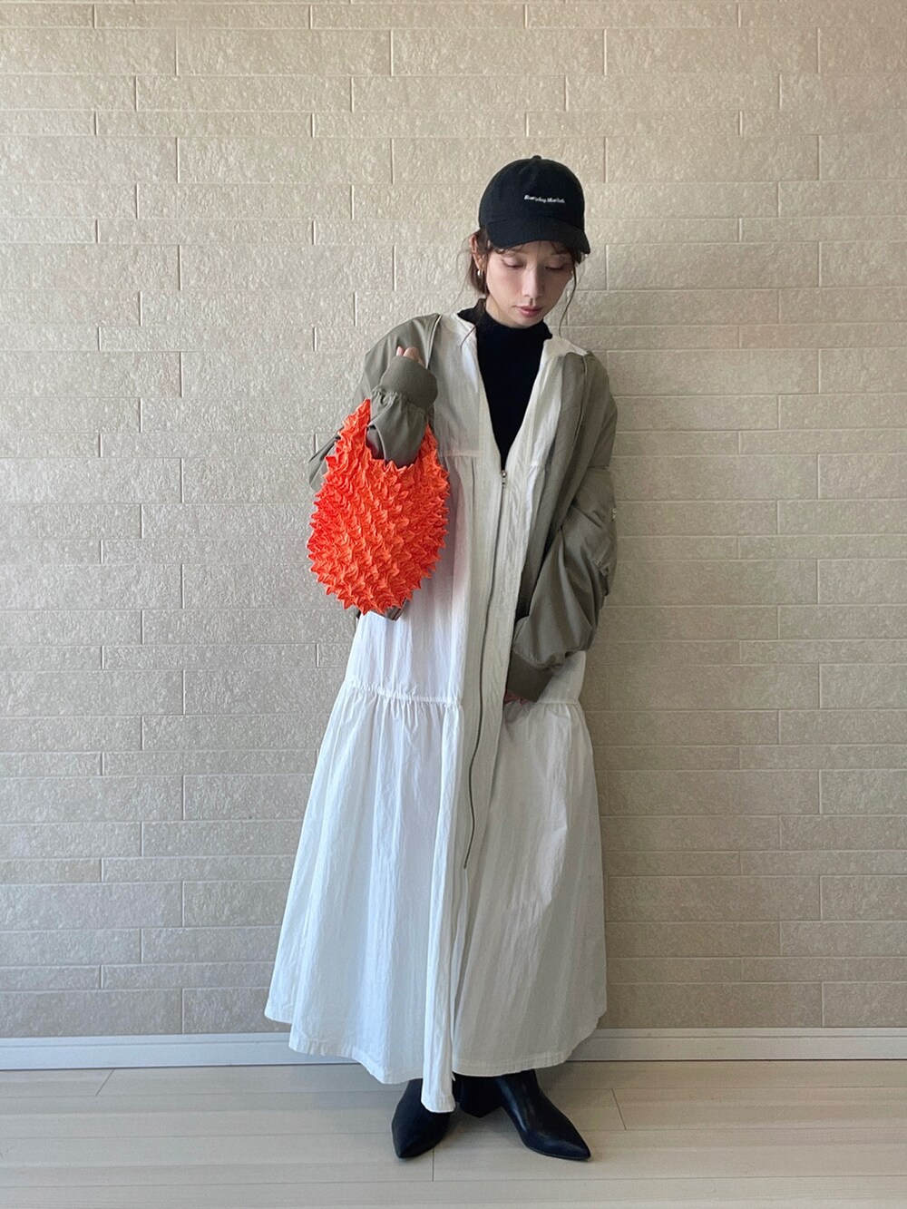 ブラック系のブーツ、ブラック系のニット/セーター、ホワイト系のワンピースを着用したレディースの秋コーディネートの2枚目の写真