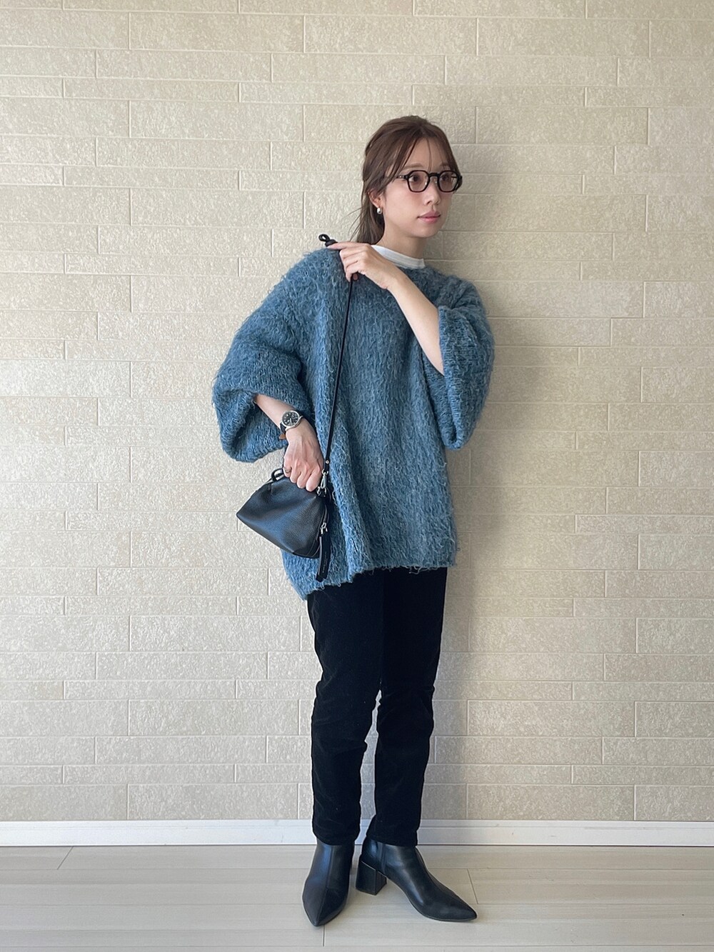 ブラック系のブーツ、ブルー系のニット/セーター、ブラック系のショルダーバッグを着用したレディースの冬コーディネートの3枚目の写真