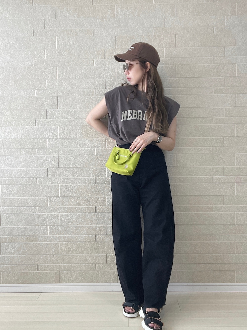 グリーン系のショルダーバッグ、ブラック系のデニムパンツ、ブラック系のサンダルを着用したレディースの夏コーディネートの2枚目の写真