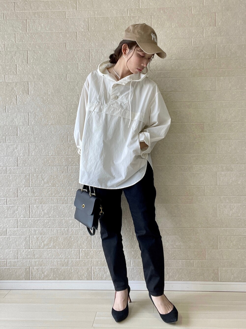 ブラック系のデニムパンツ、ホワイト系のマウンテンパーカー、ブラック系のショルダーバッグを着用したレディースの春コーディネートの2枚目の写真