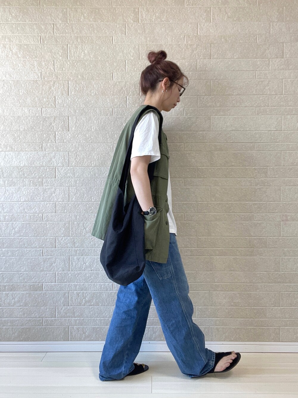 ブルー系のデニムパンツ、グリーン系のベスト、ブラック系のショルダーバッグを着用したレディースの春コーディネートの4枚目の写真