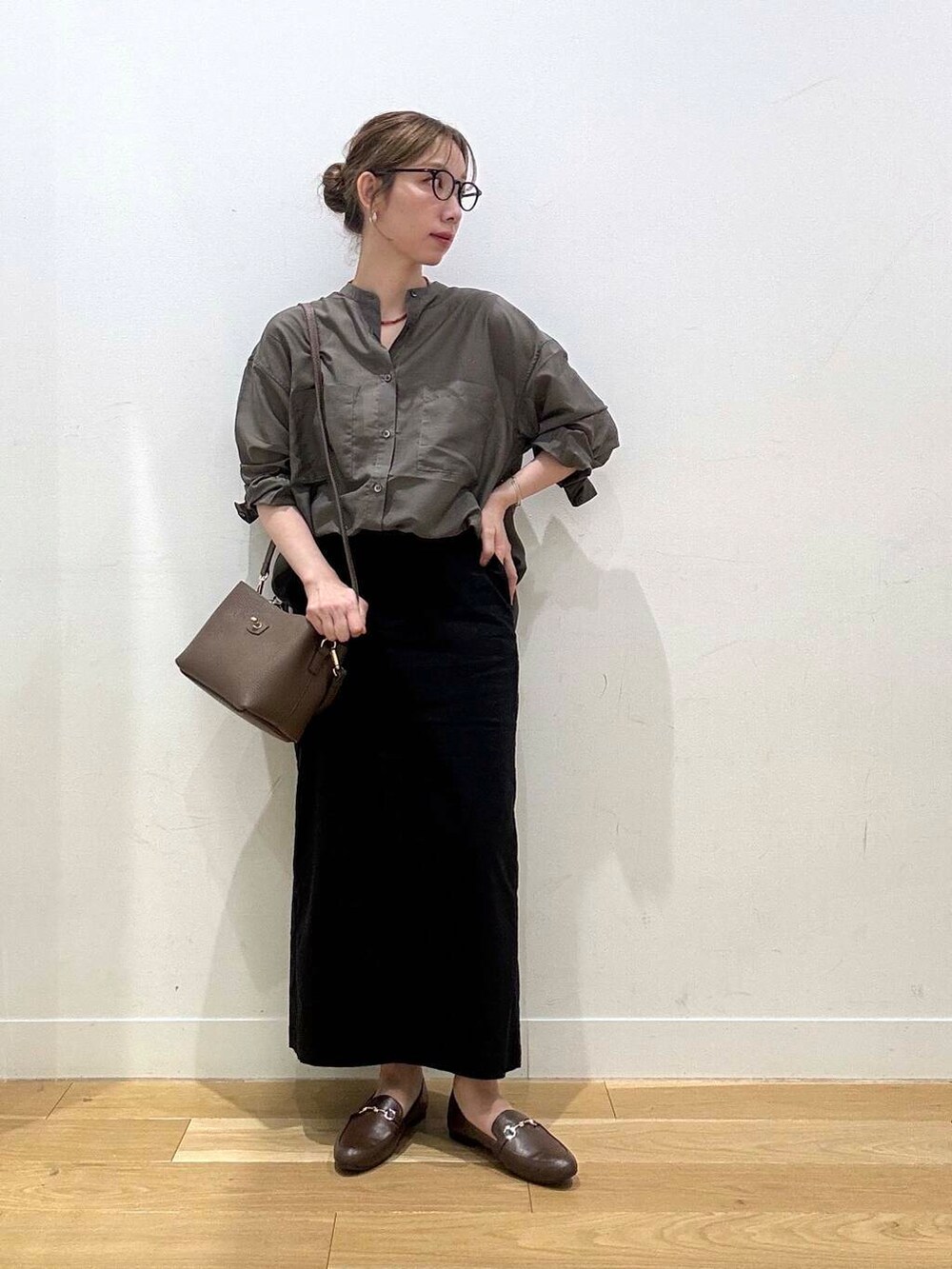 ブラウン系のローファー、ブラック系のスカート、グレー系のシャツ/ブラウスを着用したレディースの夏コーディネートの2枚目の写真