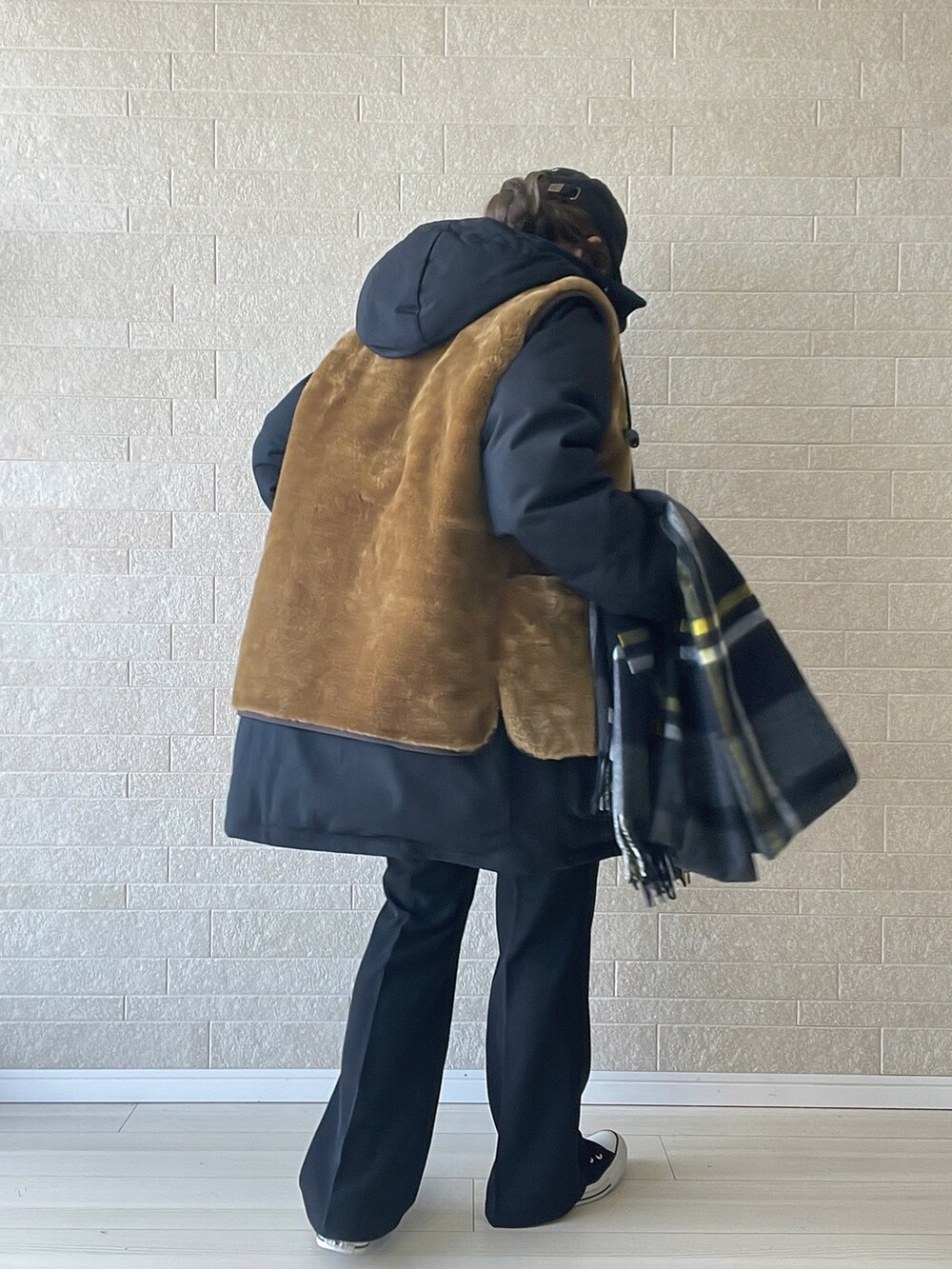 ホワイト系のニット/セーター、ブラック系のダウンジャケット/コート、ブラウン系のベストを着用したレディースの冬コーディネートの3枚目の写真