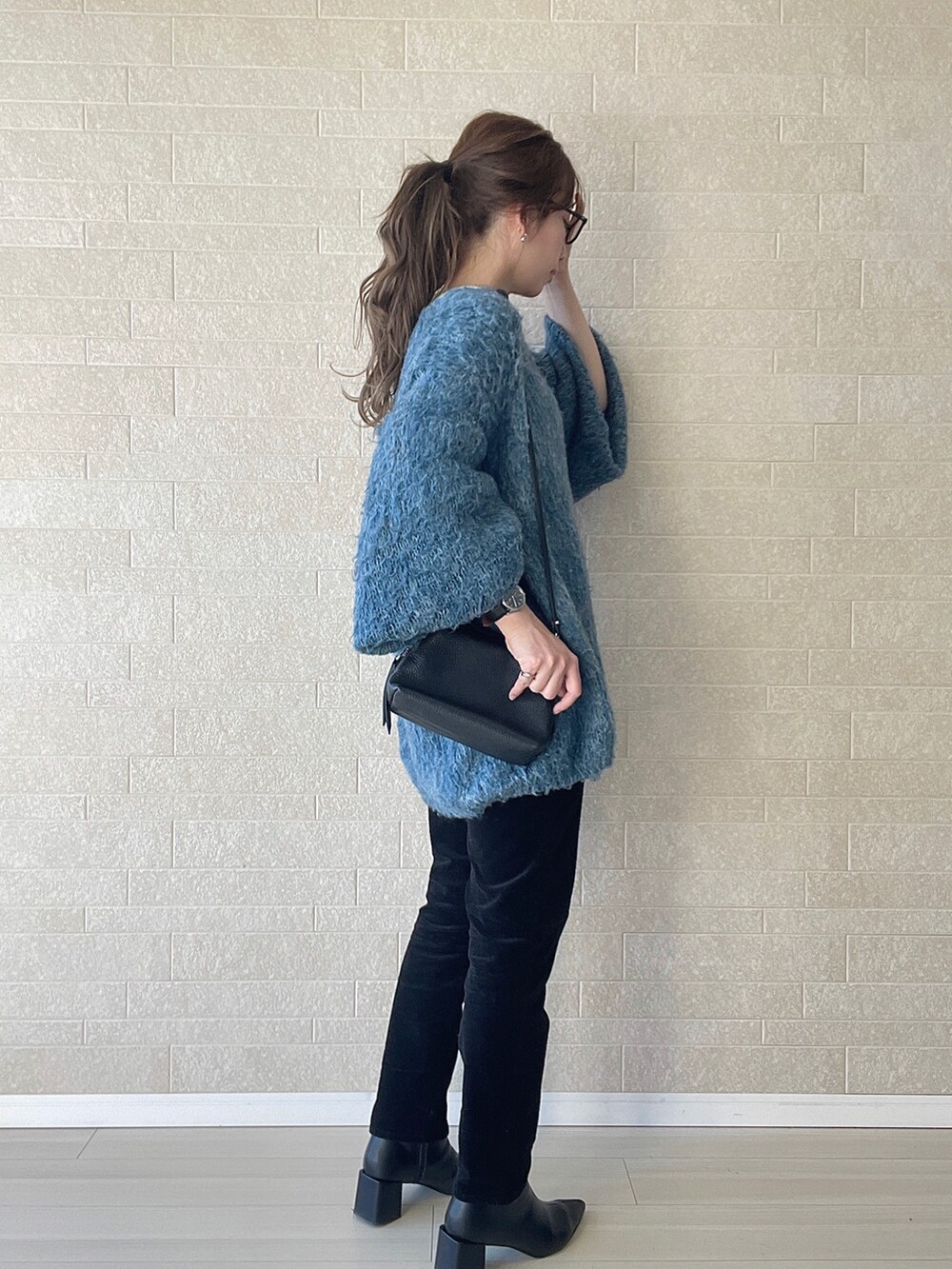 ブラック系のブーツ、ブルー系のニット/セーター、ブラック系のショルダーバッグを着用したレディースの冬コーディネートの4枚目の写真
