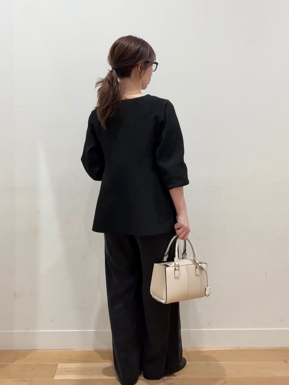 ホワイト系のハンドバッグ、ブラウン系のその他アウター、ブラック系のニット/セーターを着用したレディースの冬コーディネートの7枚目の写真