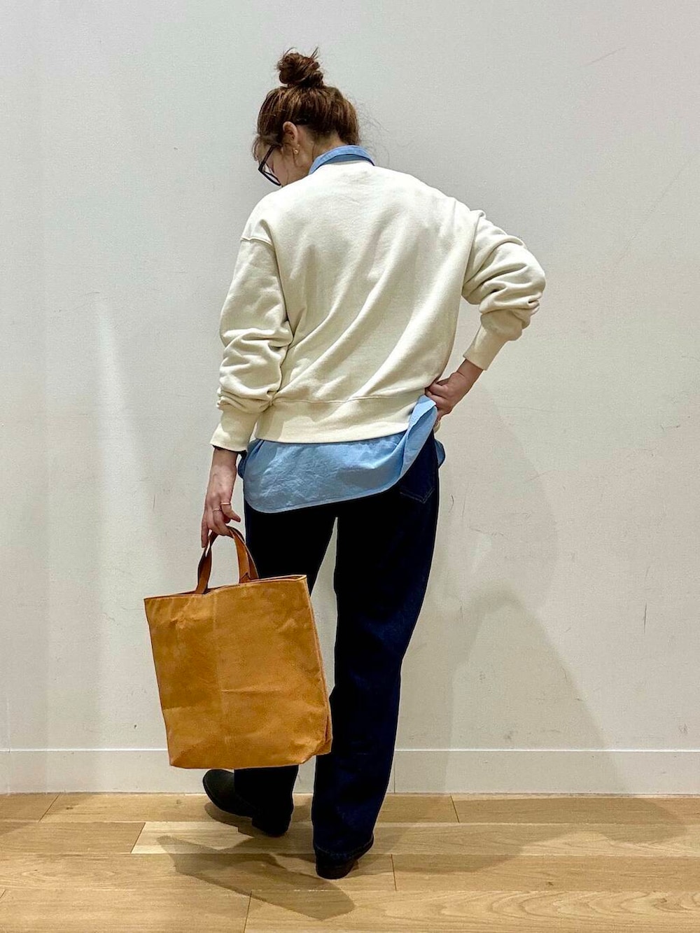 ベージュ系のステンカラーコート、イエロー系のトートバッグ、ブルー系のデニムパンツを着用したレディースの秋コーディネートの5枚目の写真