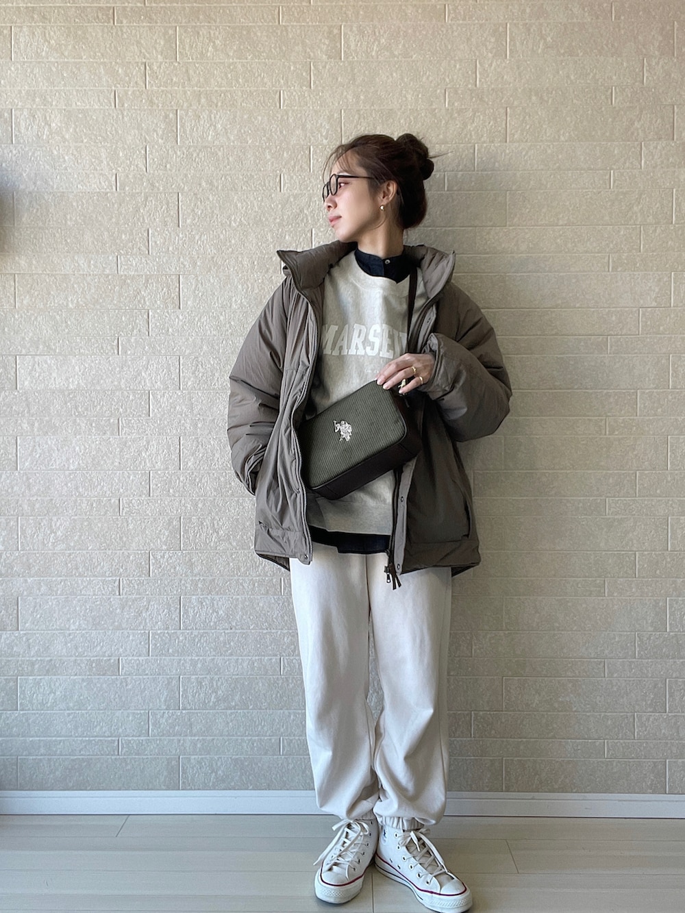 グリーン系のショルダーバッグ、ホワイト系のスニーカー、ベージュ系のスウェットを着用したレディースの冬コーディネートの2枚目の写真