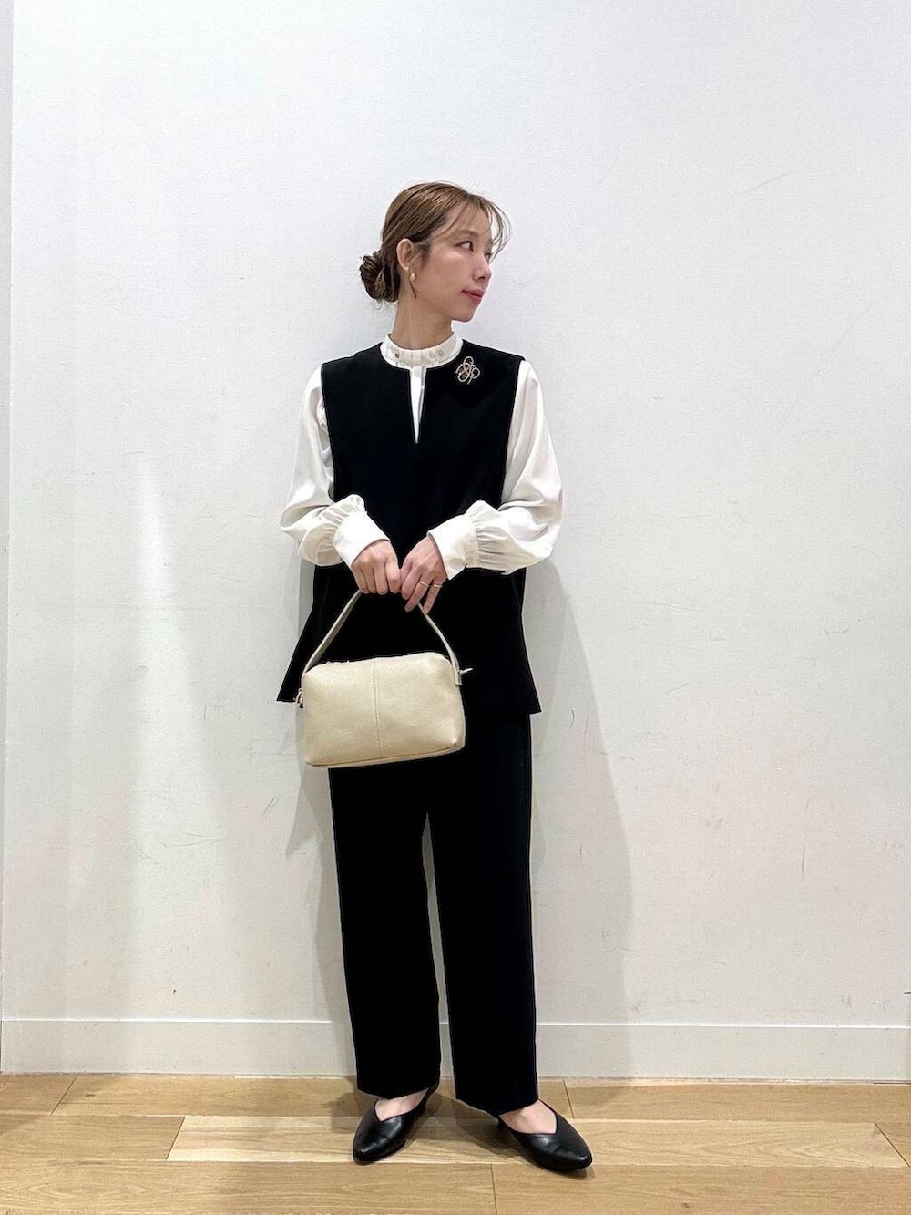 ホワイト系のショルダーバッグ、ブラック系のベスト、ホワイト系のシャツ/ブラウスを着用したレディースの冬コーディネートの2枚目の写真