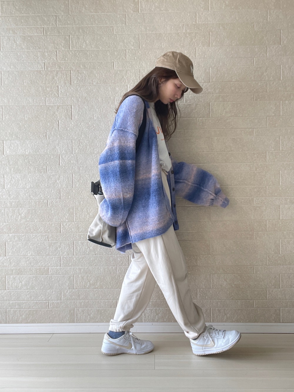 ブルー系のカーディガン/ボレロ、ブラック系のバックパック/リュック、ホワイト系のスウェットパンツを着用したレディースの秋コーディネートの2枚目の写真