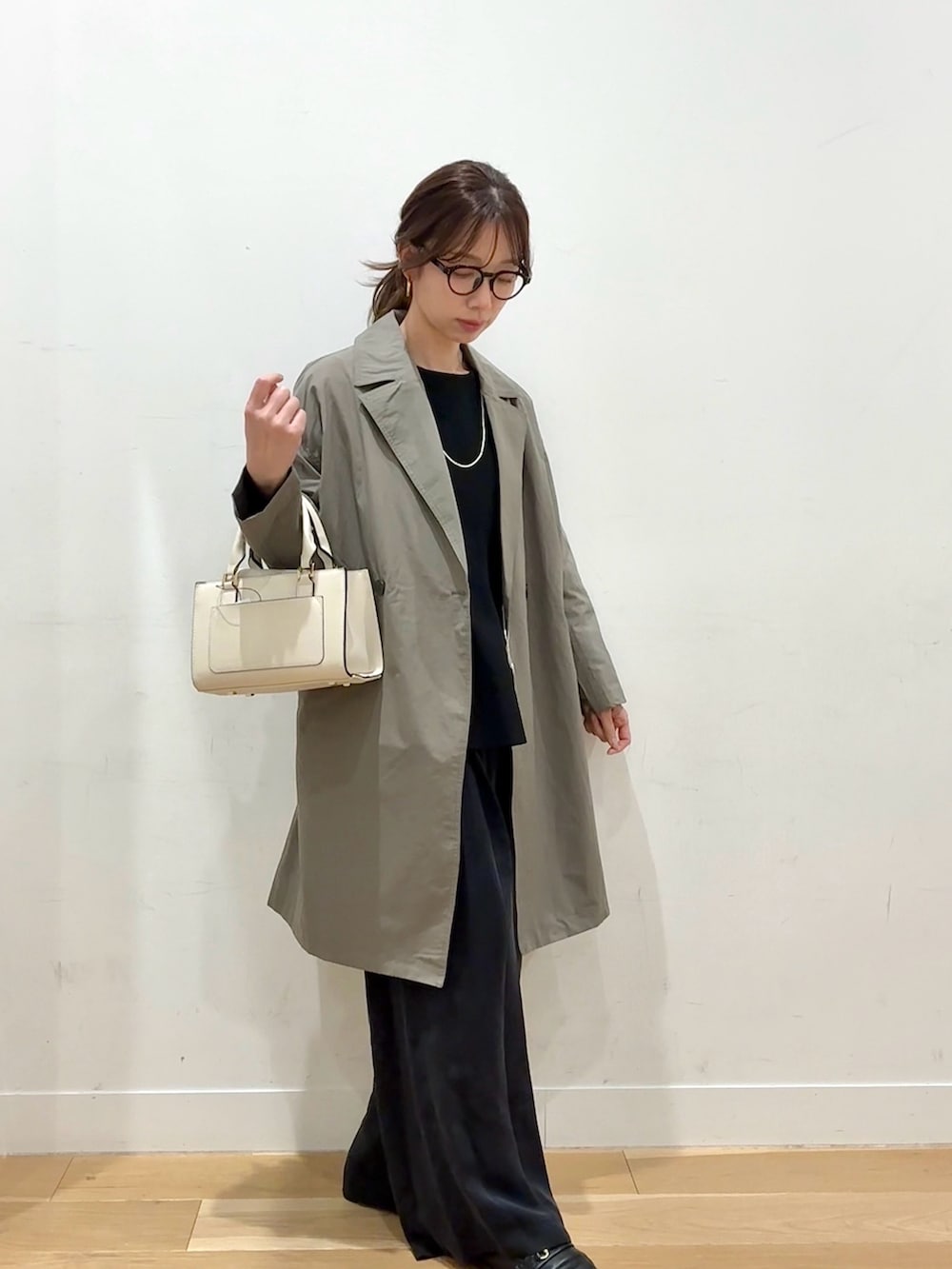 ホワイト系のハンドバッグ、ブラウン系のその他アウター、ブラック系のニット/セーターを着用したレディースの冬コーディネートの3枚目の写真