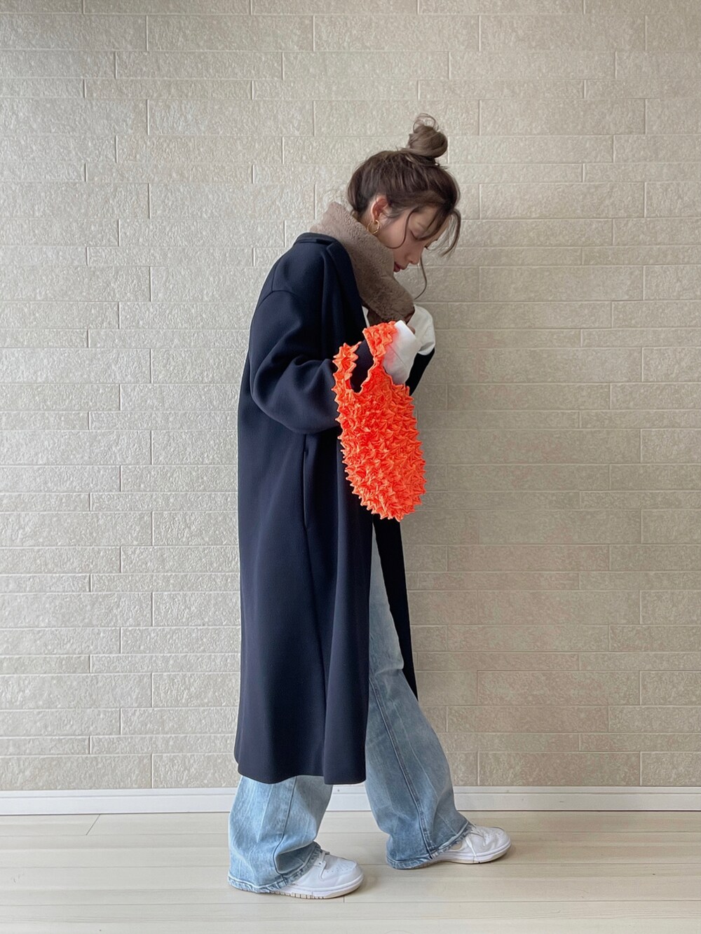 ブルー系のチェスターコート、ブルー系のデニムパンツ、オレンジ系のエコバッグ/サブバッグを着用したレディースの秋コーディネートの4枚目の写真