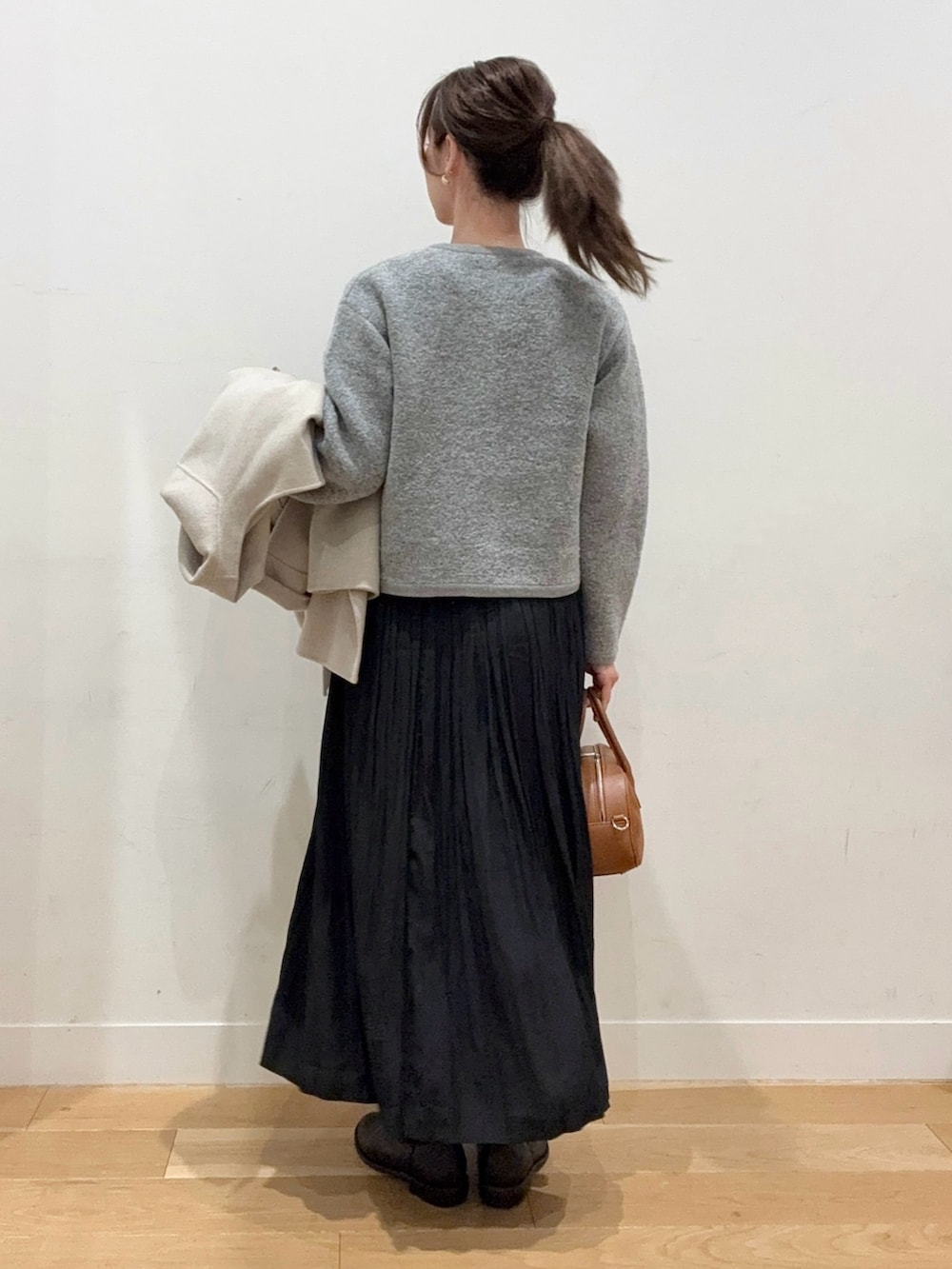 ブラウン系のショルダーバッグ、ブラック系のブーツ、ブラック系のスカートを着用したレディースの秋コーディネートの5枚目の写真