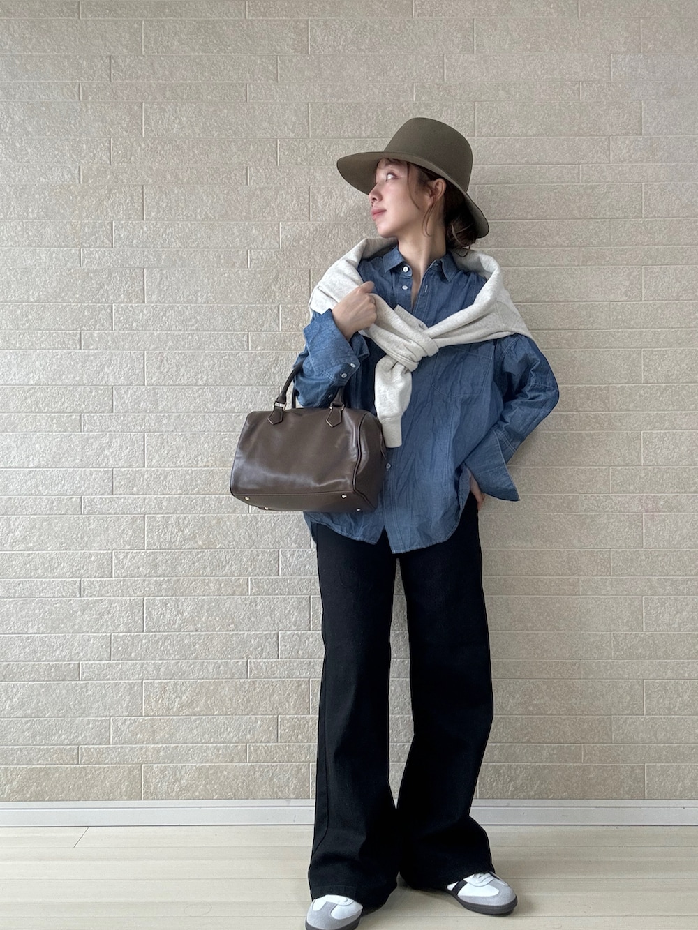 ブラック系のデニムパンツ、ブラウン系のボストンバッグ、ブルー系のシャツ/ブラウスを着用したレディースの秋コーディネートの2枚目の写真