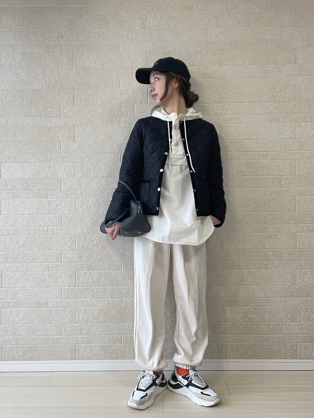 ブラック系のノーカラージャケット、ホワイト系のマウンテンパーカー、ホワイト系のスウェットパンツを着用したレディースの秋コーディネートの2枚目の写真