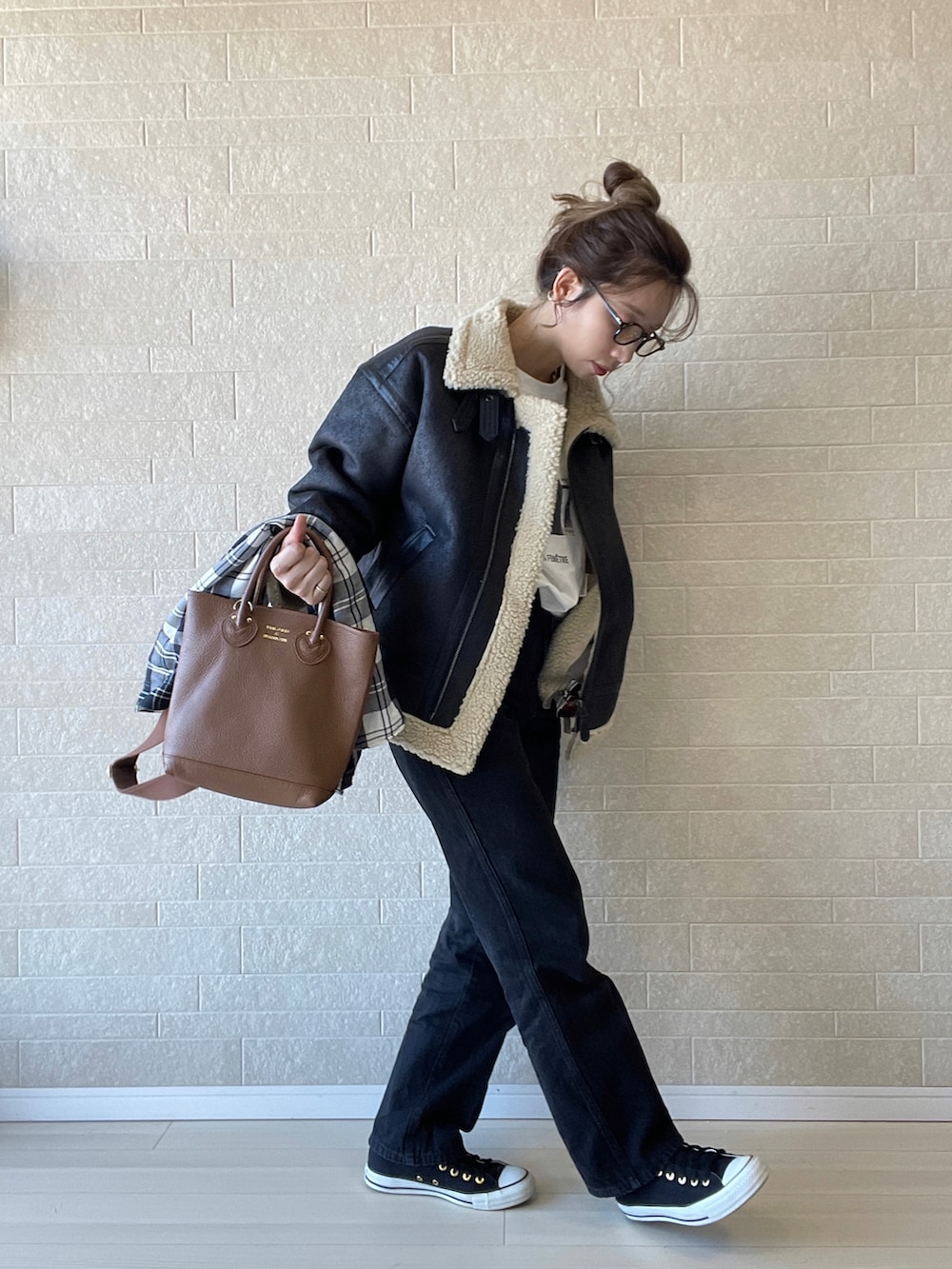 ブラック系のムートンコート、ブラック系のデニムパンツ、ブラウン系のショルダーバッグを着用したレディースの秋コーディネートの2枚目の写真