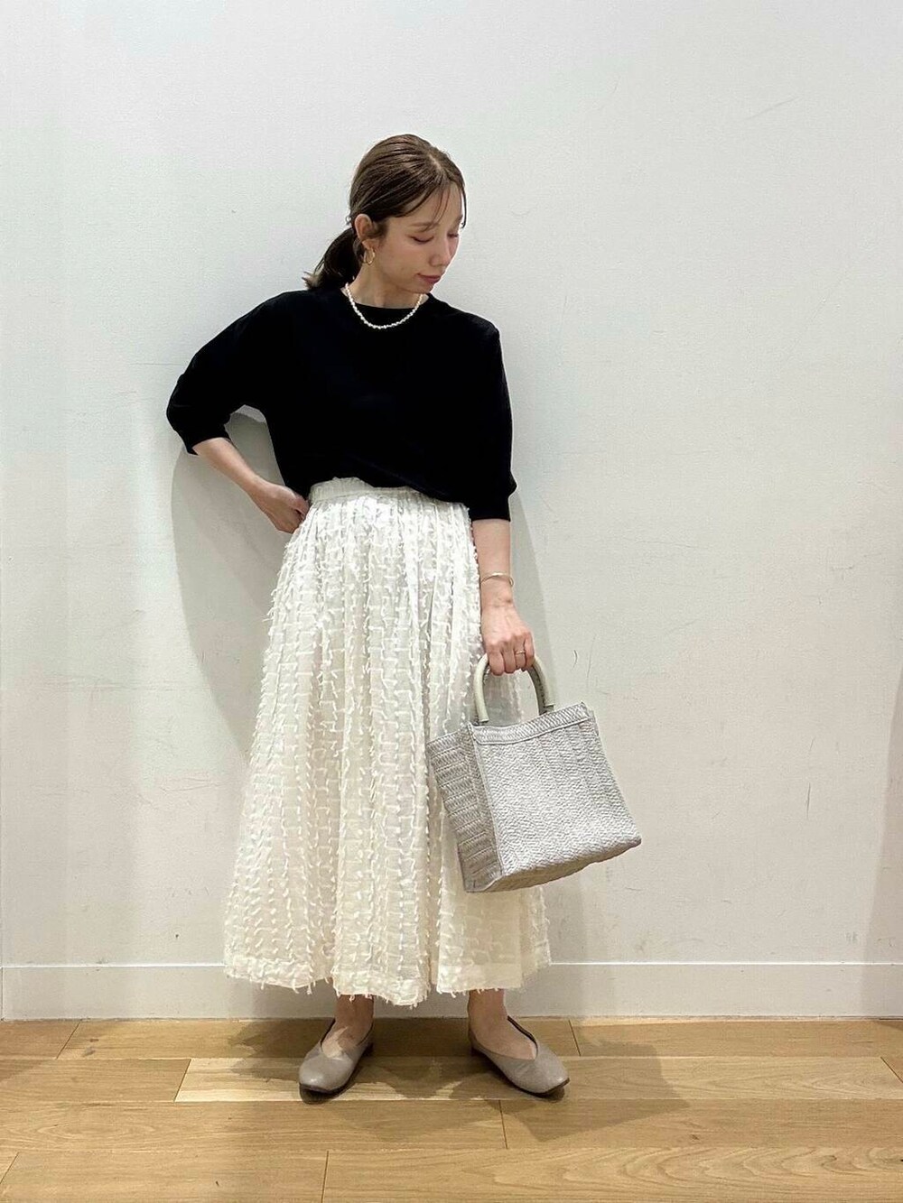 グレー系のパンプス、ブラック系のTシャツ/カットソー、ホワイト系のスカートを着用したレディースの春コーディネートの3枚目の写真