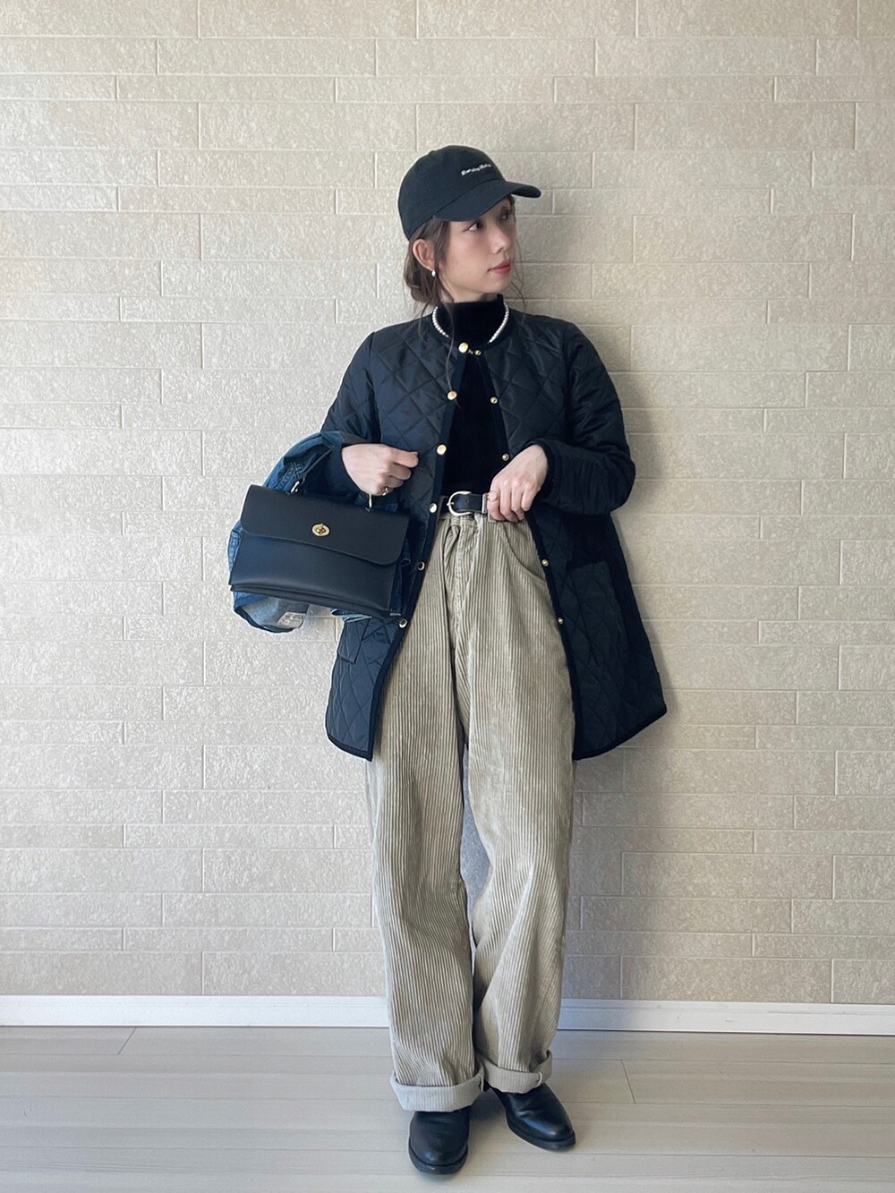 ブラック系のその他アウター、ブラック系のニット/セーター、ベージュ系のパンツを着用したレディースの冬コーディネートの2枚目の写真