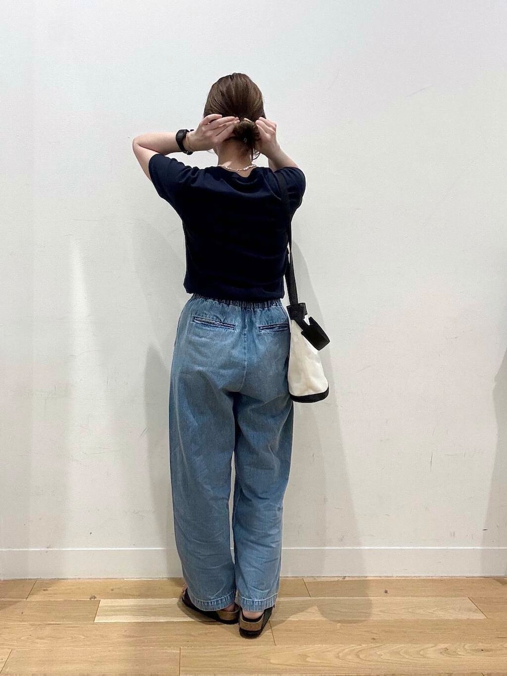 ブルー系のデニムパンツ、ブラック系のショルダーバッグ、グレー系のサンダルを着用したレディースの夏コーディネートの3枚目の写真