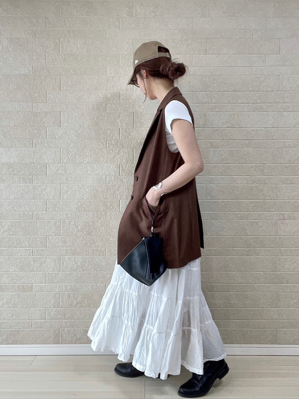 ホワイト系のTシャツ/カットソー、ブラウン系のベスト、ブラック系のハンドバッグを着用したレディースの春コーディネートの3枚目の写真