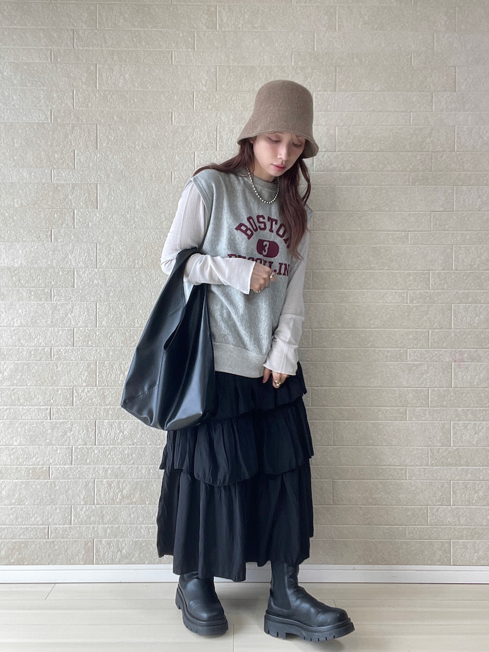 ブラック系のスカート、ブラック系のトートバッグ、グレー系のベストを着用したレディースの春コーディネートの2枚目の写真