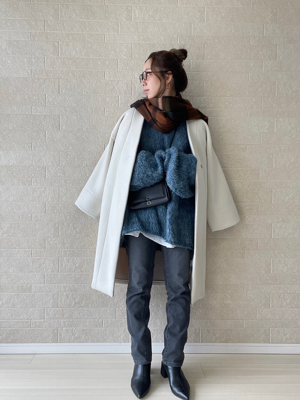 グレー系のデニムパンツ、ブラック系のブーツ、ブルー系のニット/セーターを着用したレディースの冬コーディネートの3枚目の写真