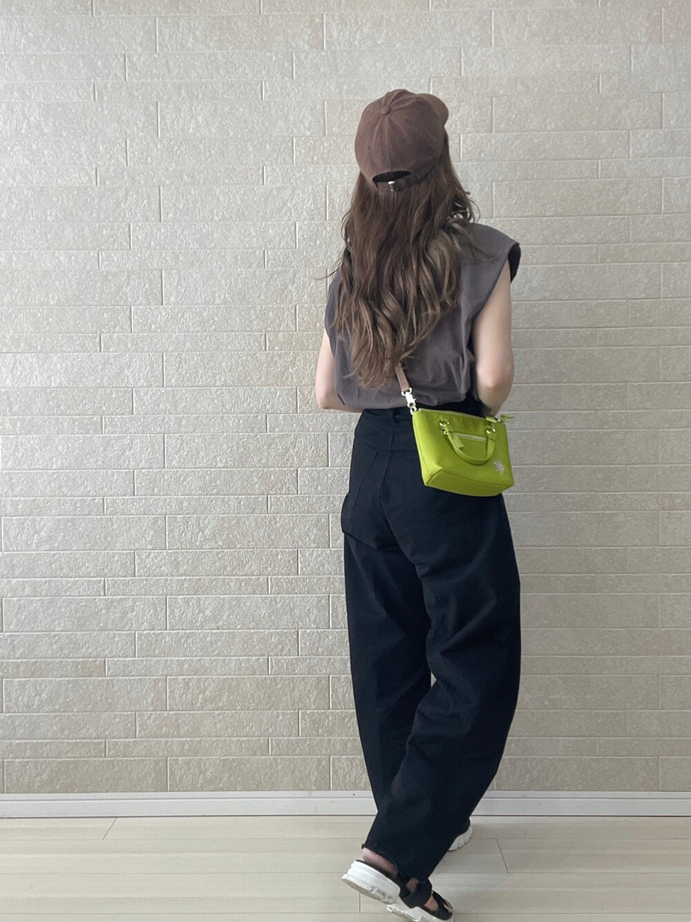 グリーン系のショルダーバッグ、ブラック系のデニムパンツ、ブラック系のサンダルを着用したレディースの夏コーディネートの3枚目の写真