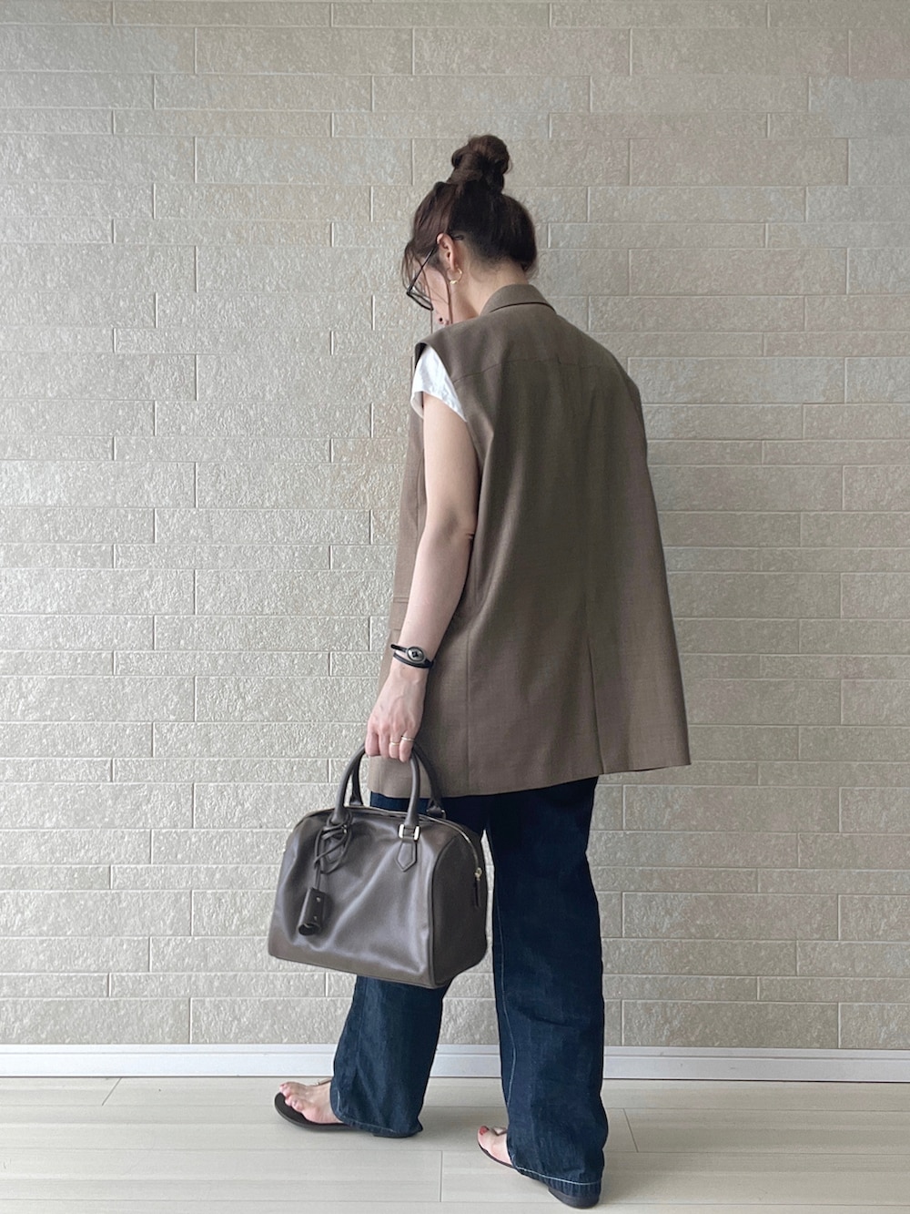 ブルー系のサロペット/オーバーオール、ブラウン系のベスト、ブラウン系のボストンバッグを着用したレディースの夏コーディネートの3枚目の写真