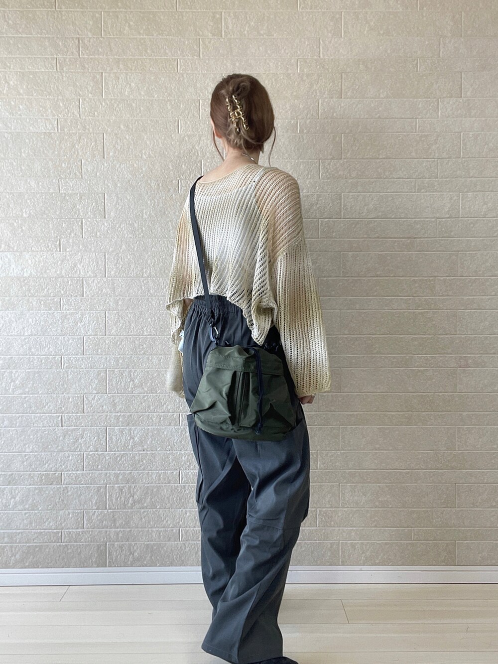 イエロー系のニット/セーター、グレー系のカーゴパンツ、グリーン系のショルダーバッグを着用したレディースの秋コーディネートの2枚目の写真