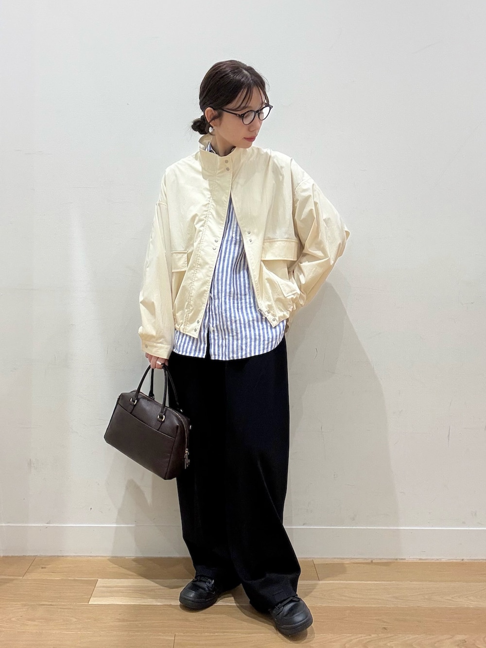 ホワイト系のブルゾン、ブラウン系のボストンバッグ、ブラック系のその他パンツを着用したレディースの春コーディネートの5枚目の写真