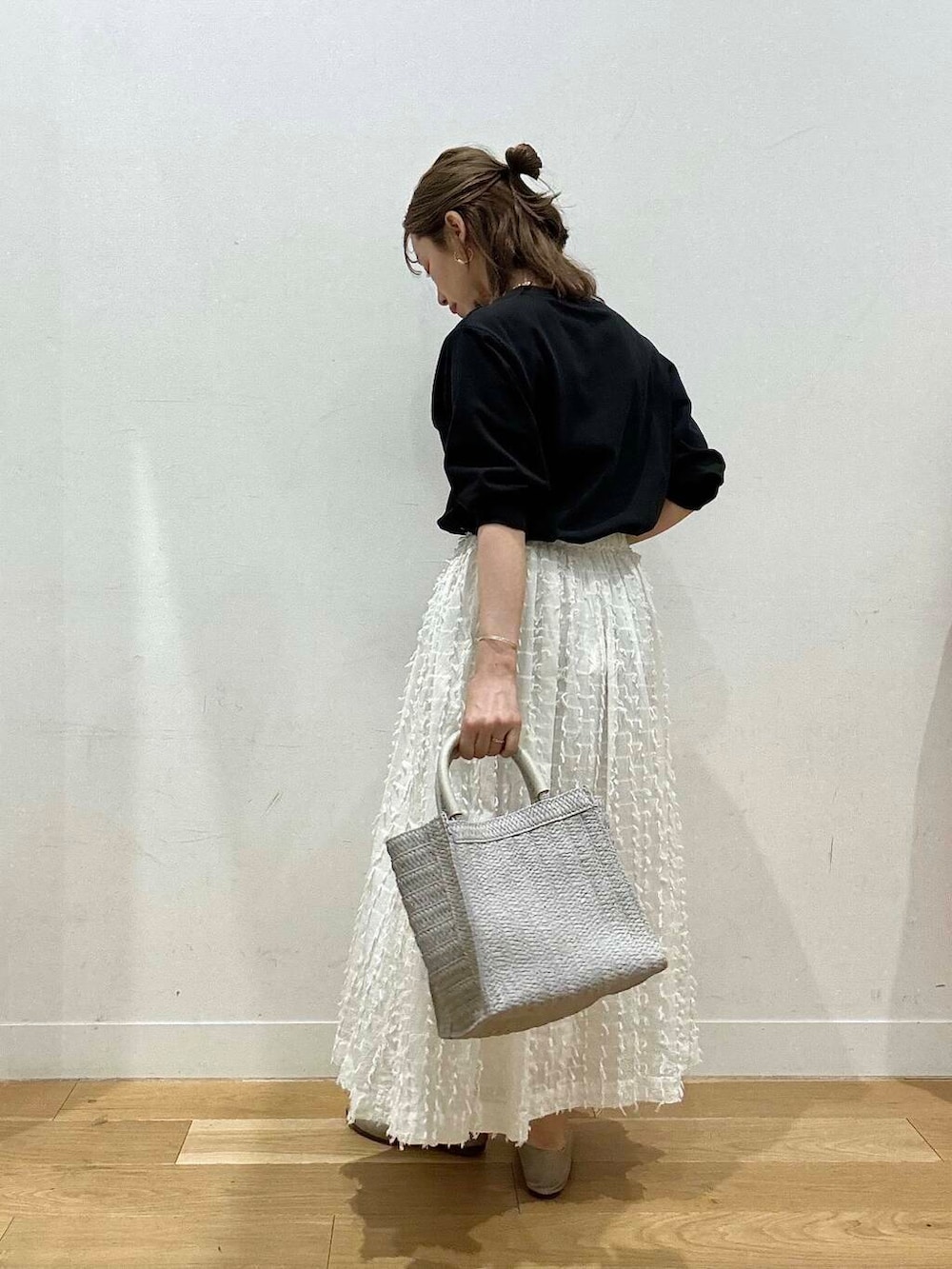 グレー系のパンプス、ブラック系のTシャツ/カットソー、ホワイト系のスカートを着用したレディースの春コーディネートの2枚目の写真