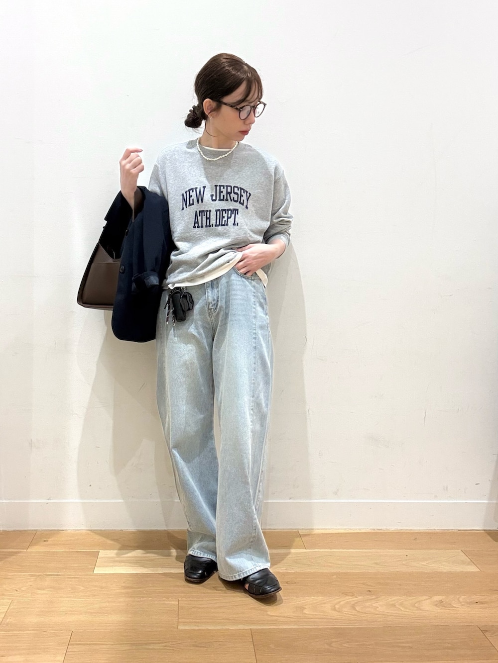 ブラウン系のハンドバッグ、ブルー系のデニムパンツ、ホワイト系のTシャツ/カットソーを着用したレディースの秋コーディネートの2枚目の写真