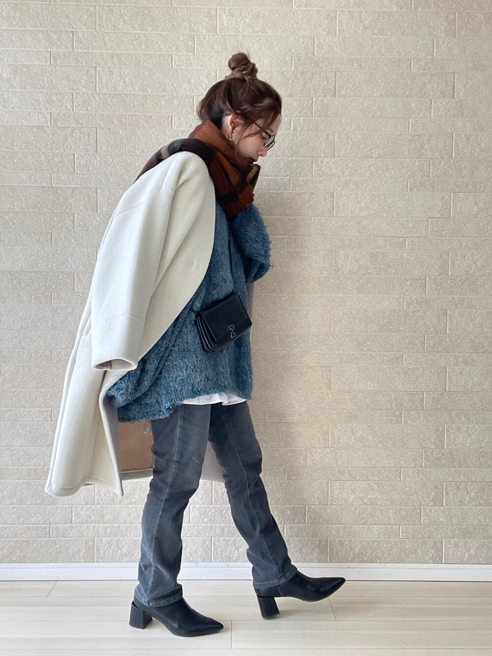 グレー系のデニムパンツ、ブラック系のブーツ、ブルー系のニット/セーターを着用したレディースの冬コーディネートの2枚目の写真