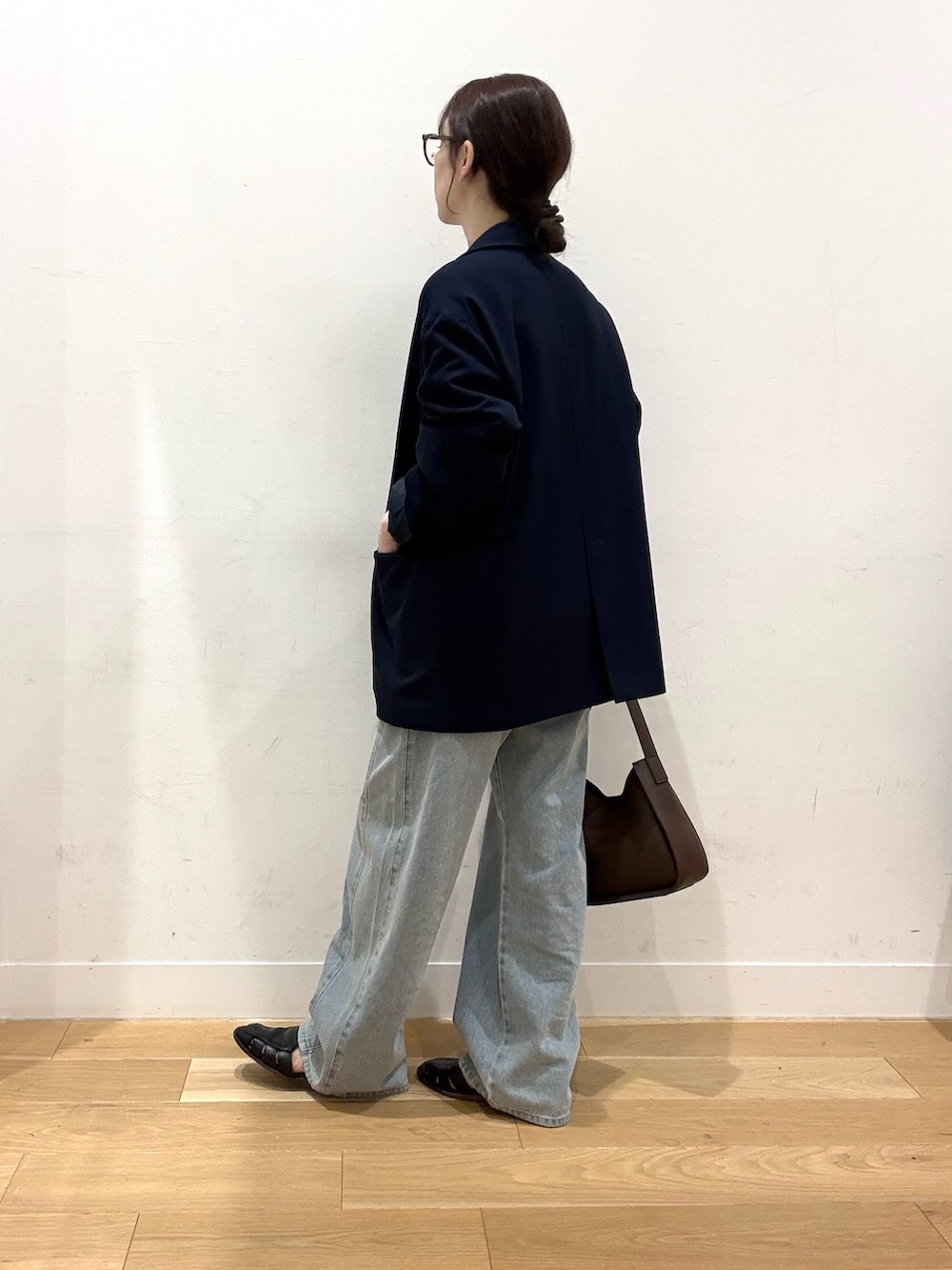 ブラウン系のハンドバッグ、ブルー系のデニムパンツ、ホワイト系のTシャツ/カットソーを着用したレディースの秋コーディネートの3枚目の写真
