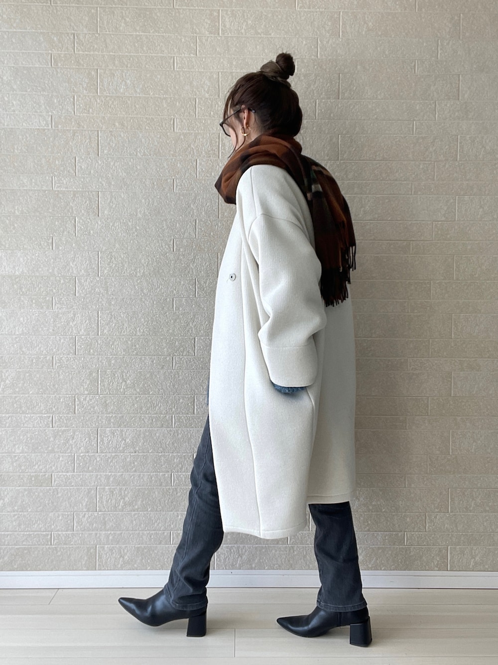 グレー系のデニムパンツ、ブラック系のブーツ、ブルー系のニット/セーターを着用したレディースの冬コーディネートの4枚目の写真