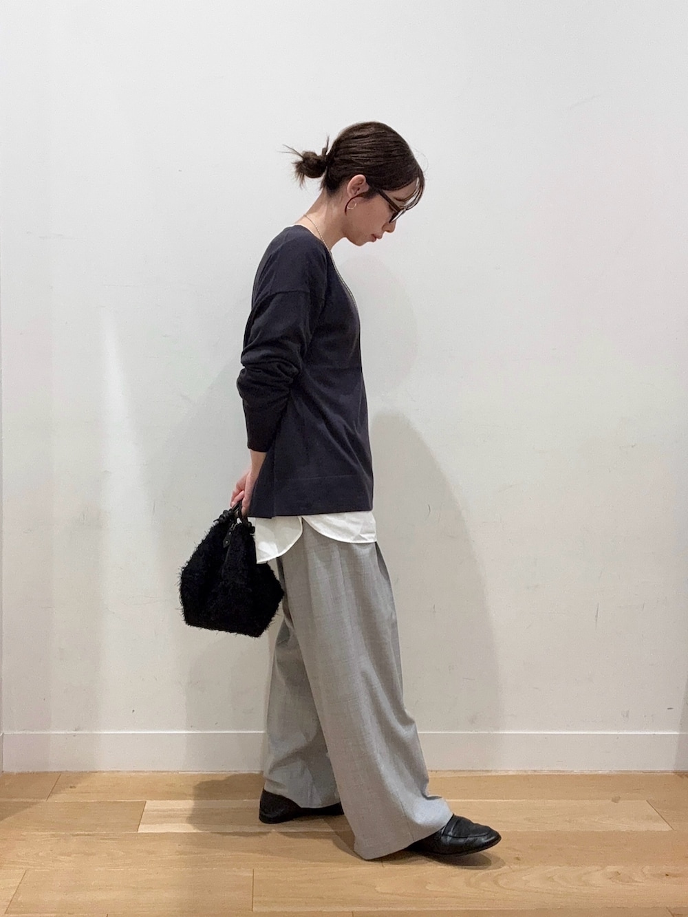 グレー系のニット/セーター、ホワイト系のダウンジャケット/コート、ブラック系のハンドバッグを着用したレディースの秋コーディネートの3枚目の写真