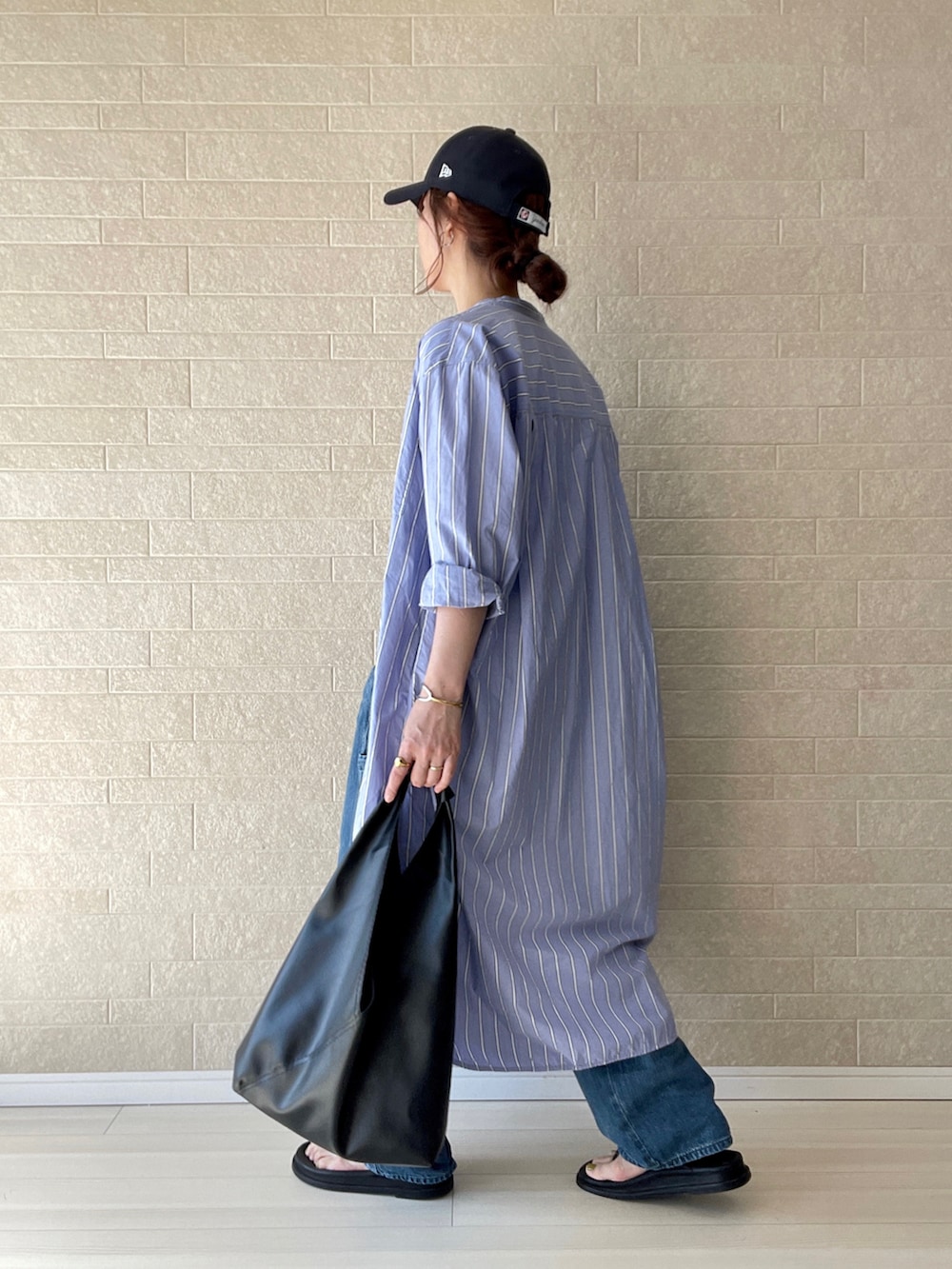 ブルー系のデニムパンツ、ホワイト系のTシャツ/カットソー、ブラック系のトートバッグを着用したレディースの春コーディネートの3枚目の写真