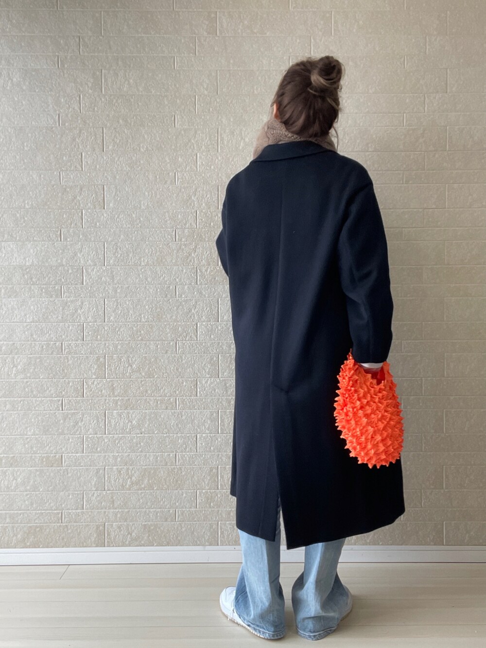 ブルー系のチェスターコート、ブルー系のデニムパンツ、オレンジ系のエコバッグ/サブバッグを着用したレディースの秋コーディネートの5枚目の写真