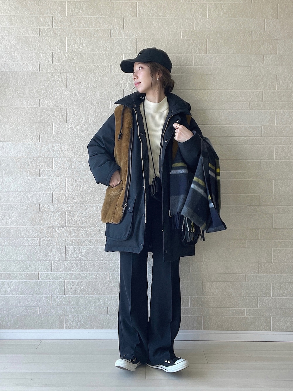 ホワイト系のニット/セーター、ブラック系のダウンジャケット/コート、ブラウン系のベストを着用したレディースの冬コーディネートの2枚目の写真