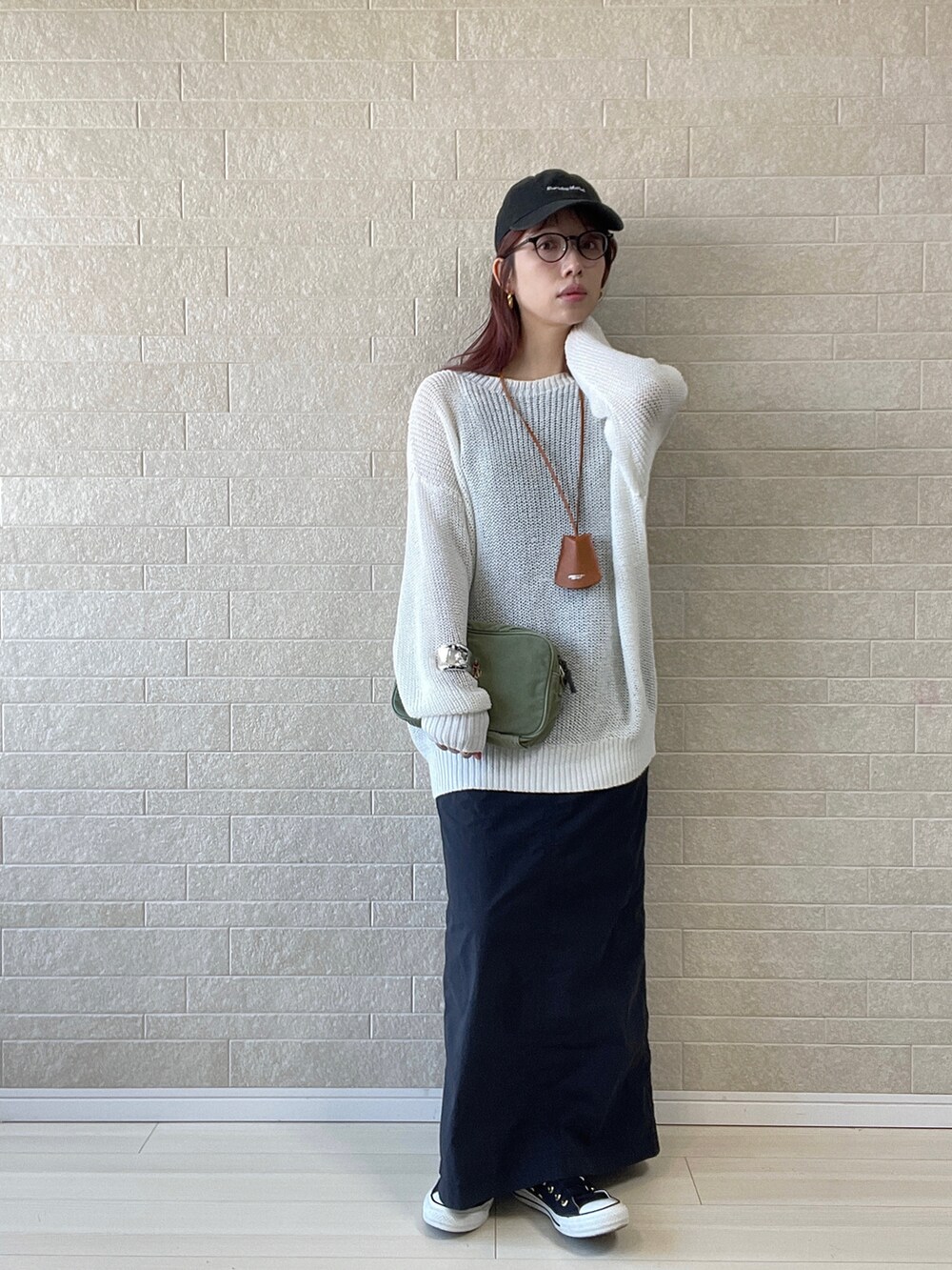 グリーン系のショルダーバッグ、ブラック系のワンピース、ブラック系のスニーカーを着用したレディースの春コーディネートの4枚目の写真