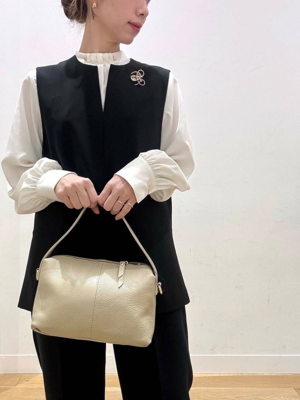 ホワイト系のショルダーバッグ、ブラック系のベスト、ホワイト系のシャツ/ブラウスを着用したレディースの冬コーディネートの3枚目の写真