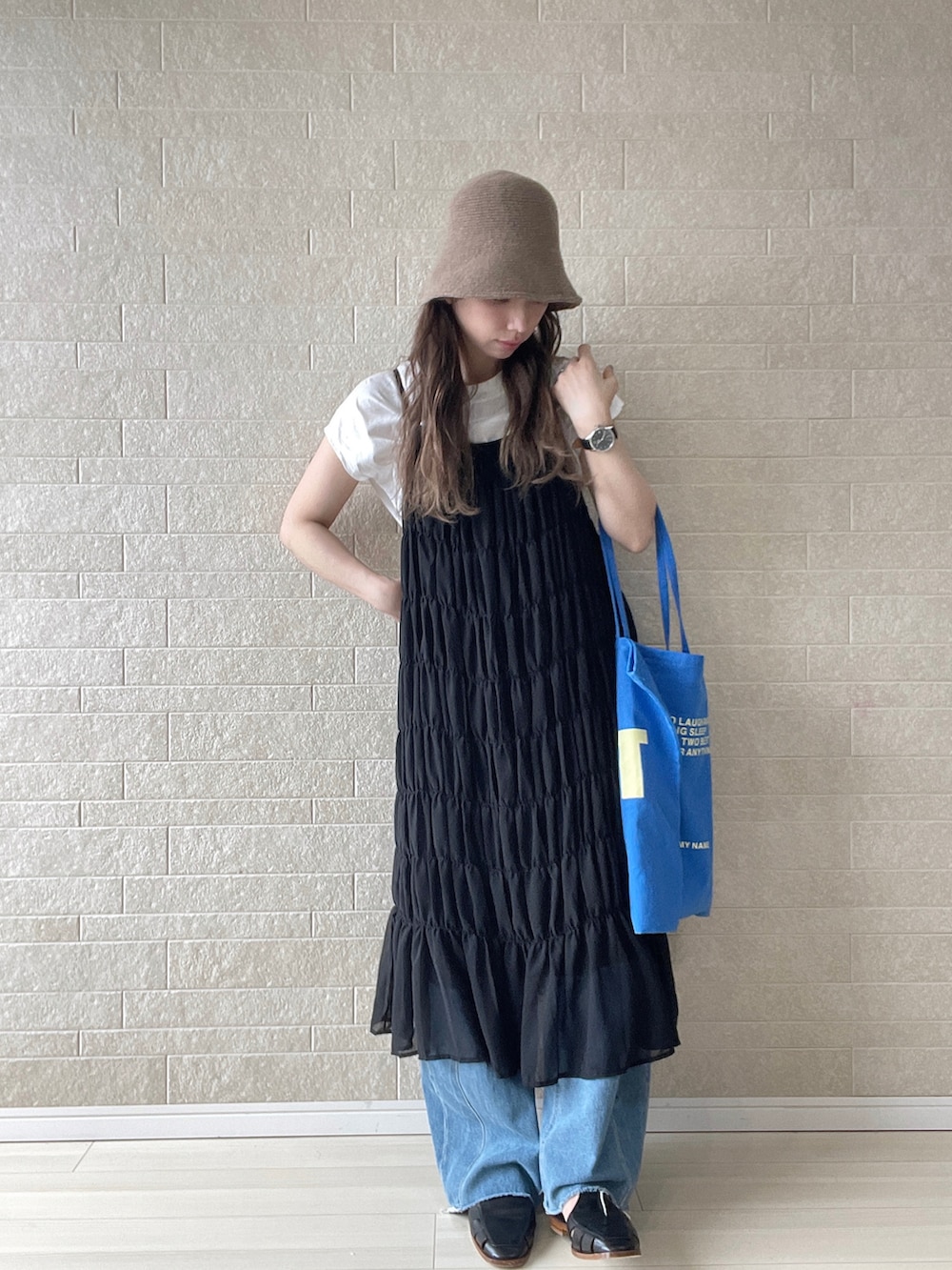 ブラック系のワンピース、ブルー系のトートバッグ、ブルー系のデニムパンツを着用したレディースの夏コーディネートの4枚目の写真