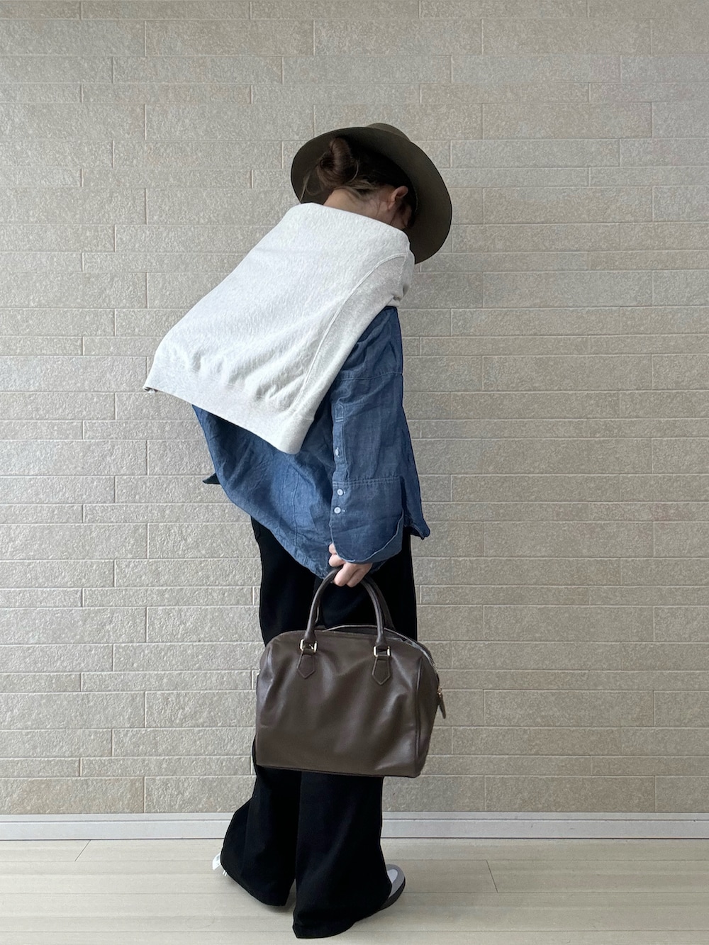 ブラック系のデニムパンツ、ブラウン系のボストンバッグ、ブルー系のシャツ/ブラウスを着用したレディースの秋コーディネートの3枚目の写真