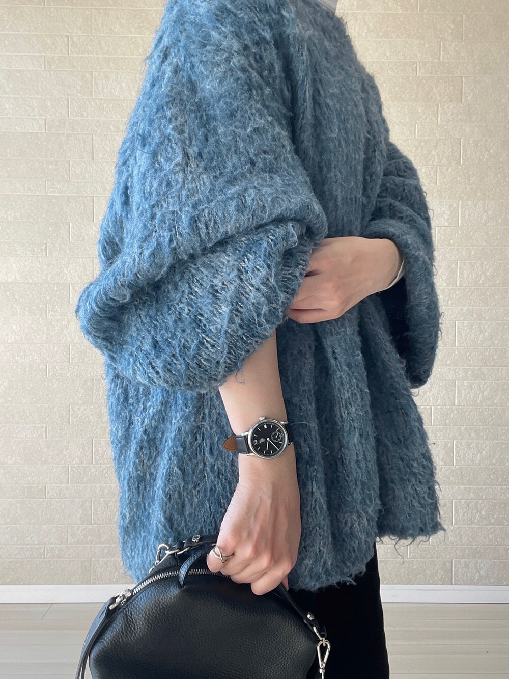 ブラック系のブーツ、ブルー系のニット/セーター、ブラック系のショルダーバッグを着用したレディースの冬コーディネートの5枚目の写真