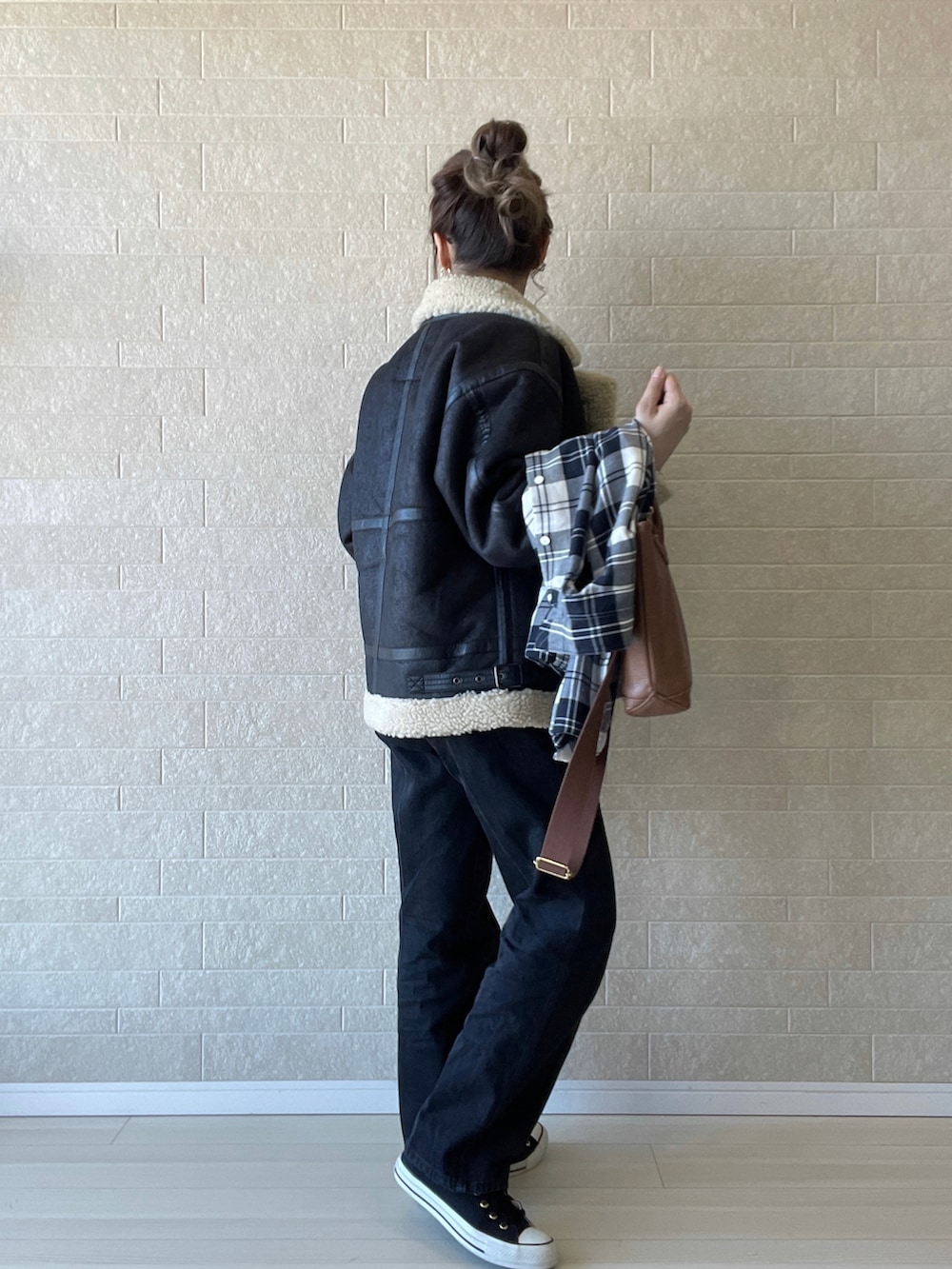 ブラック系のムートンコート、ブラック系のデニムパンツ、ブラウン系のショルダーバッグを着用したレディースの秋コーディネートの3枚目の写真