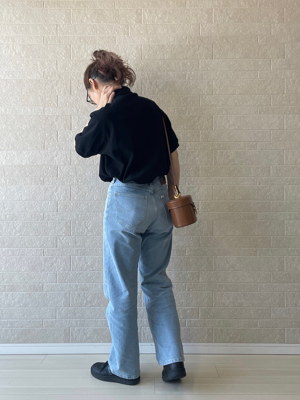 ブルー系のデニムパンツ、ブラック系のポロシャツ、ブラック系のスニーカーを着用したレディースの夏コーディネートの4枚目の写真