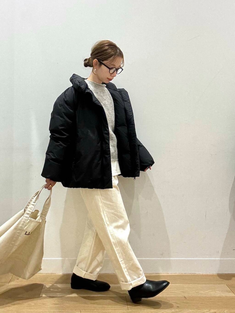 ホワイト系のトートバッグ、ベージュ系のデニムパンツ、ブラック系のブーツを着用したレディースの冬コーディネートの2枚目の写真