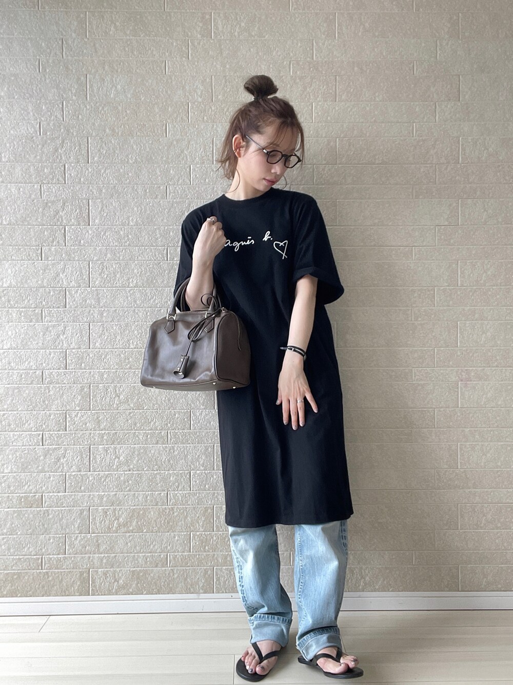 ブラック系のワンピース、ブラウン系のボストンバッグ、ブルー系のデニムパンツを着用したレディースの夏コーディネートの2枚目の写真